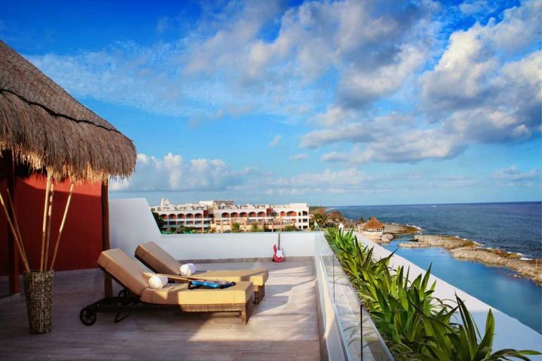 Rooftop terrace with lounge chairs overlooking the ocean.