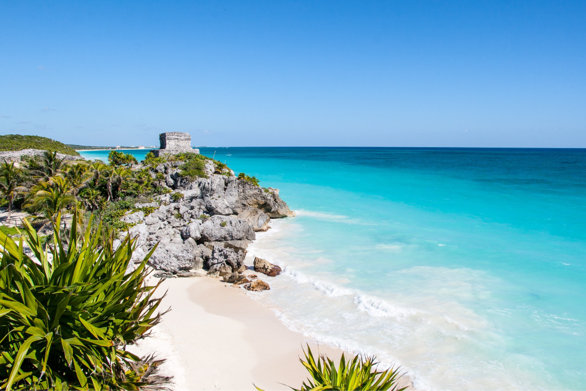 A hidden beach with a rocky cliffside monument in the background.