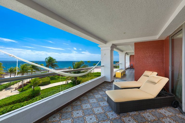 Balcony with lounge chairs and a hammock overlooking the ocean.
