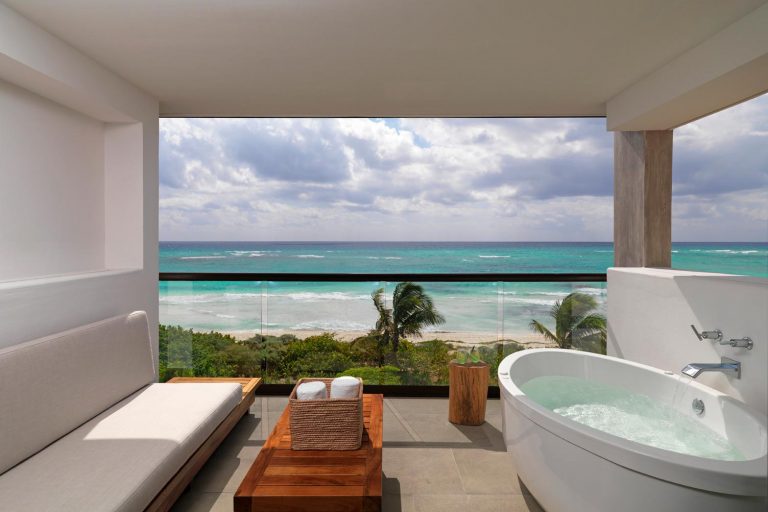 A balcony with lounge chairs and a jacuzzi overlooking the ocean.