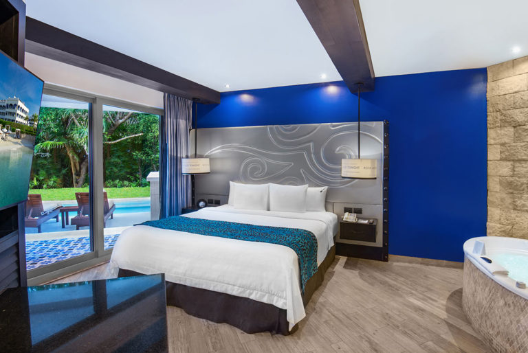 King Bed suite with swim up pool patio in the background.
