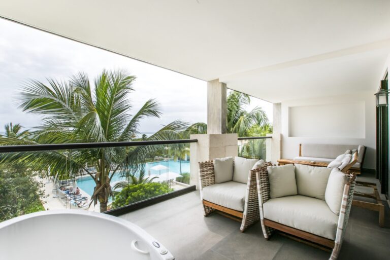 Balcony area with lounge chairs and a jacuzzi overlooking the resort pool.