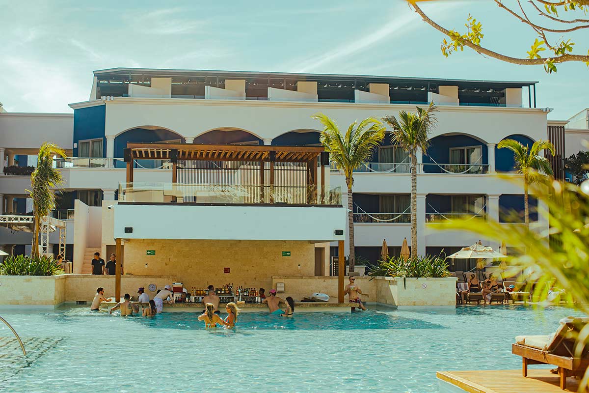 A poolside bar with guests sitting in front of it.