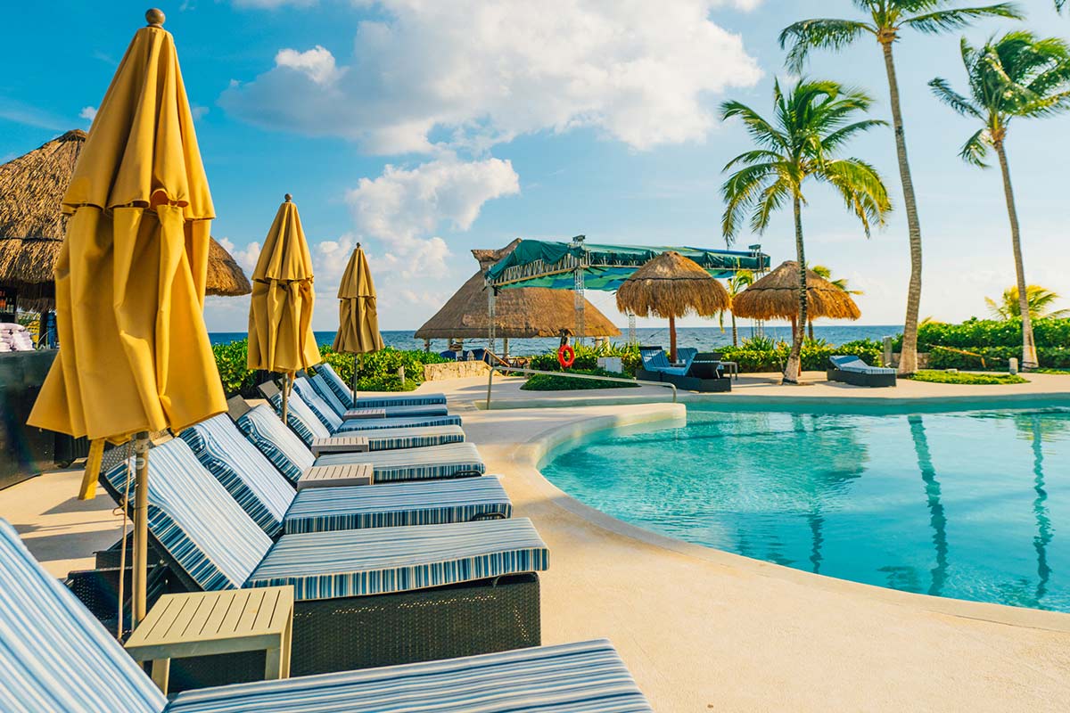 Poolside lounge chairs with an ocean view in the background.