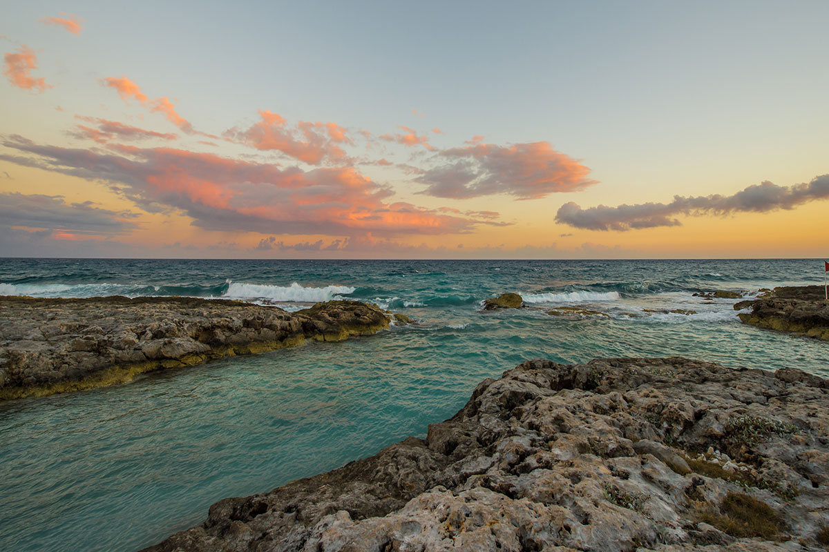Ocean waves crashing on rocks during sunset.