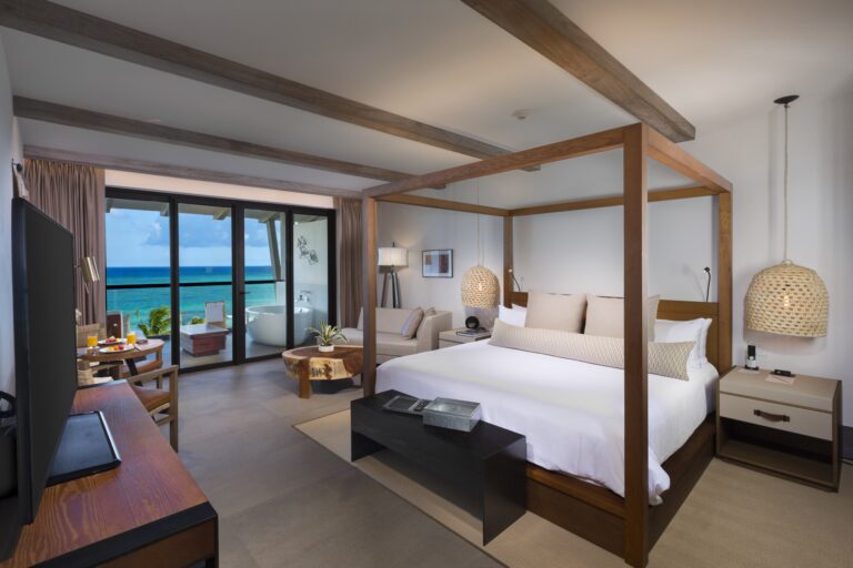 Main bedroom area of an Alcoba suite with an ocean view balcony.
