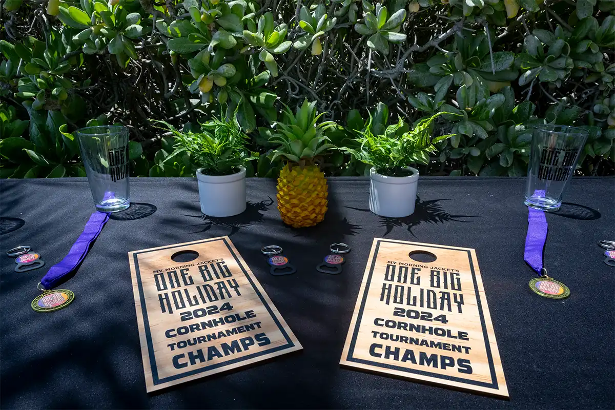 Cornhole tournament wooden board trophies displayed on a table.