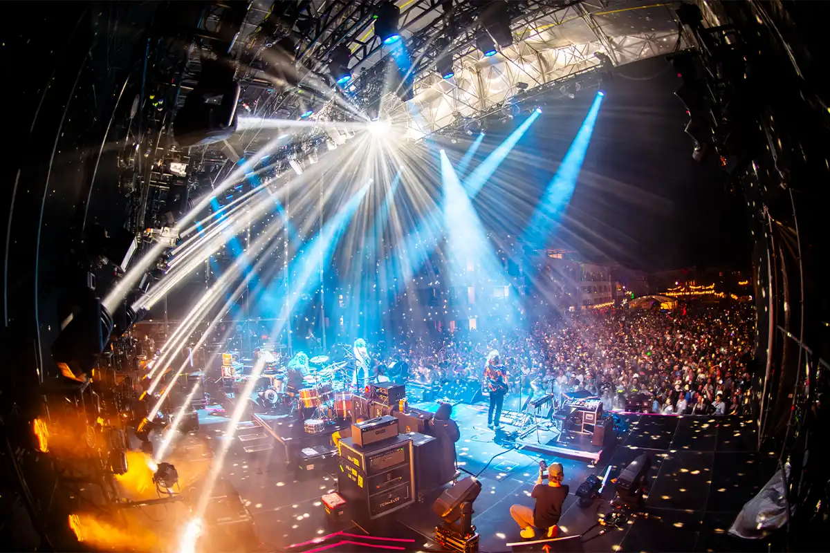 View from behind the band looking out towards the crowd with a bright disco ball shining light across the stage.