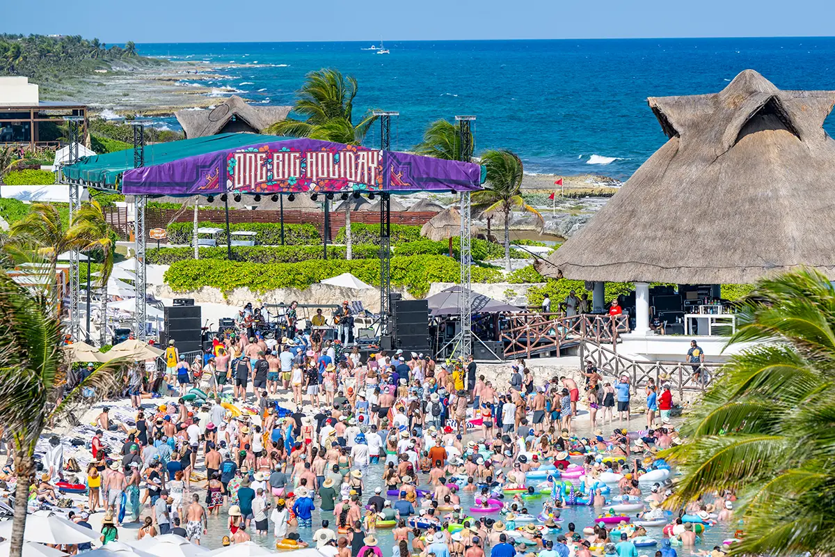 A raised aerial view of the Beach Stage crowd watching a daytime concert in a lagoon.