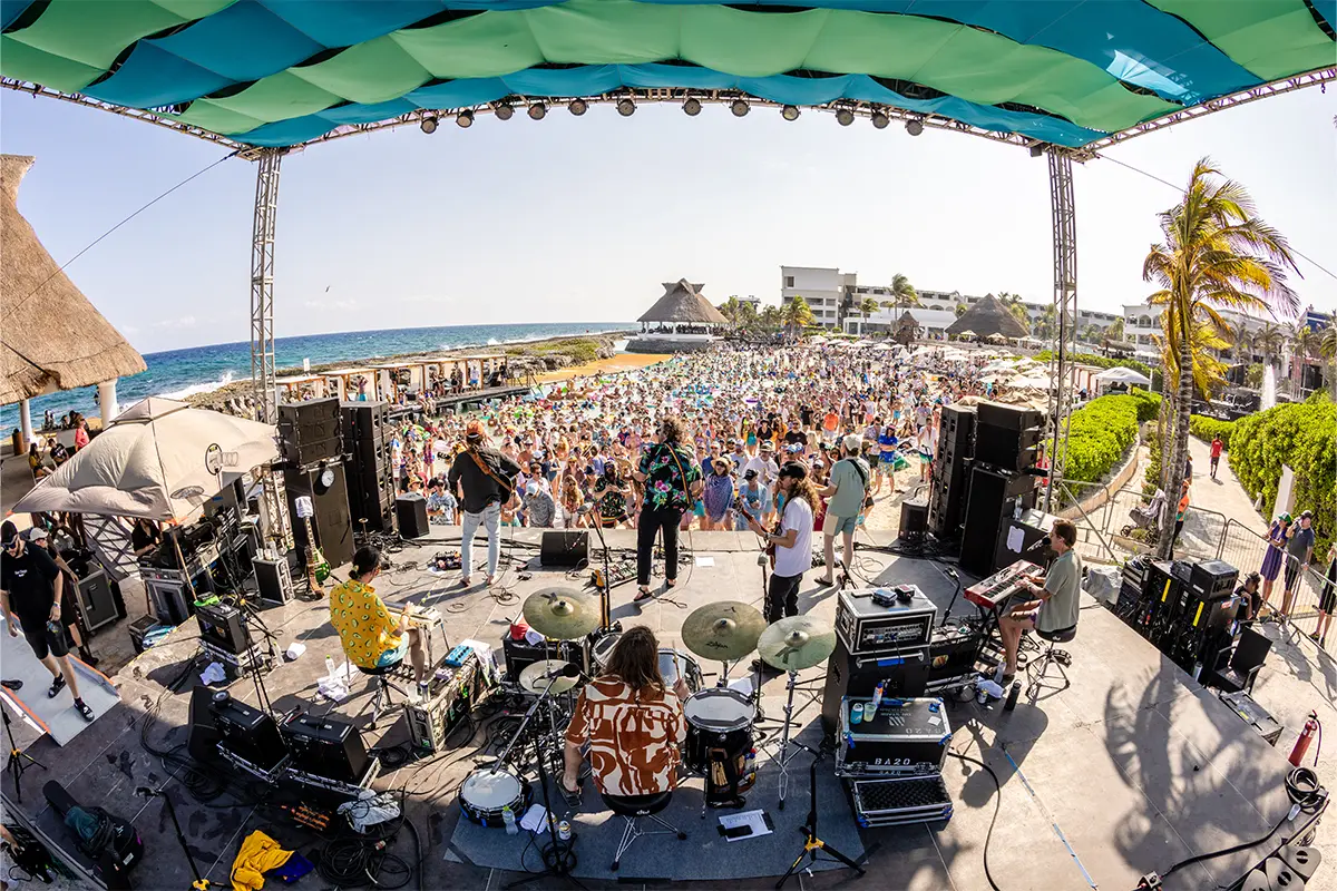 A photo from behind a band performing on the Beach Stage looking out towards the crowd.