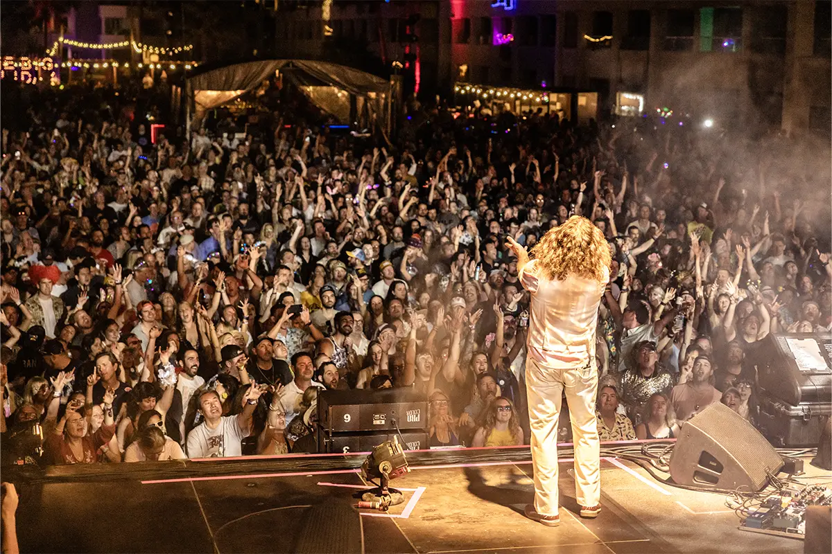 Jim James singing towards the crowd with their hands up.